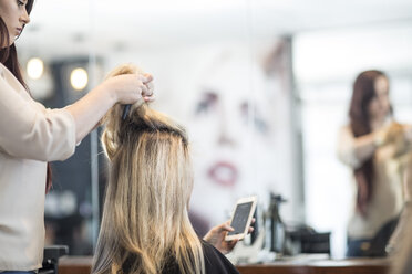 Hairdresser in hair salon checking hair of customer - ZEF008198