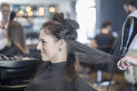 Frau im Friseursalon lässt sich die Haare trocknen, lizenzfreies Stockfoto