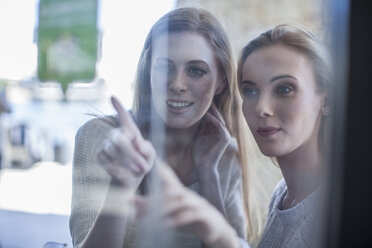 Young women looking through shop window - ZEF008264