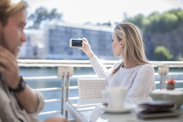 Woman taking photo with smartphone, man talking on teh phone - ZEF008270