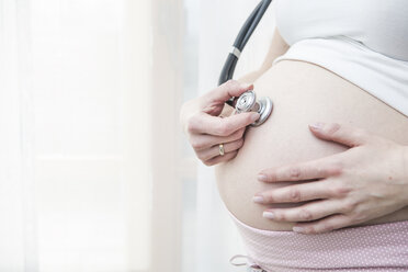 Pregnant woman holding stethoscope in front of her belly - VTF000495