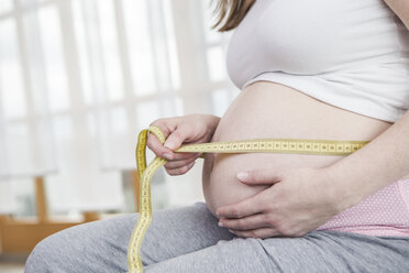 Cropped view of young woman measuring her waist with tape measure