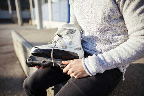 Nahaufnahme eines jungen Mannes, der einen Inline-Skate hält - DAWF000488