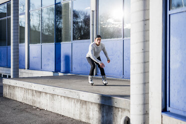 Young man inline skating along a building - DAWF000501