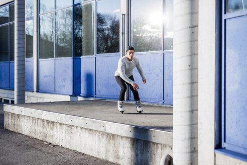 Junger Mann auf Inline-Skates entlang eines Gebäudes - DAWF000501