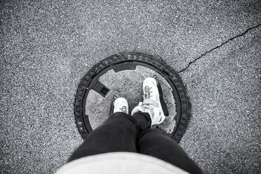 Young man with inline skates standing on manhole cover - DAWF000505