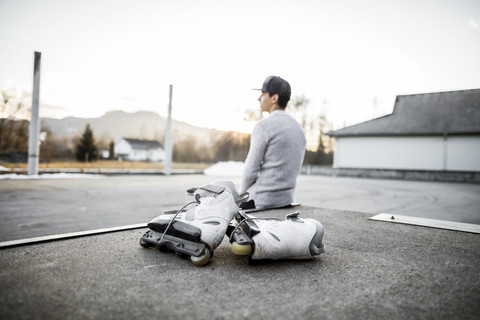 Young man sitting on ramp with inline skates stock photo