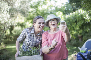 Happy senior woman and teenage girl gardening together taking a selfie - ZEF008293