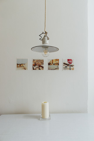 Reihe von vier Polaroids an einer Wand, alte Deckenleuchte und eine Kerze auf dem Tisch, lizenzfreies Stockfoto
