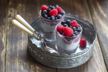 Two glasses of chia pudding with blueberries and raspberries on metal tray - SARF002512