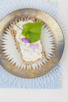 Frischkäse mit Veilchen und Wasabi auf Knäckebrot, essbare Blüten - GWF004594