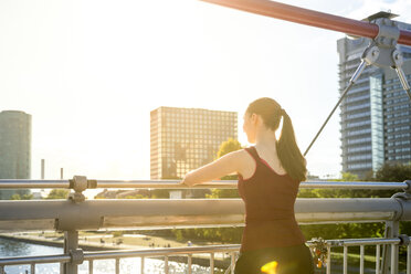 Deutschland, Frankfurt, junger Sportler steht auf einer Brücke und betrachtet die Aussicht - PUF000469