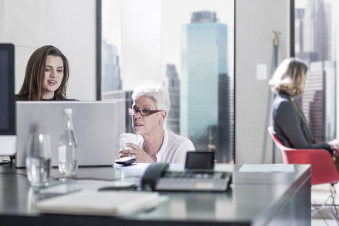 Zwei Frauen im Büro, die am Laptop diskutieren - ZEF008305