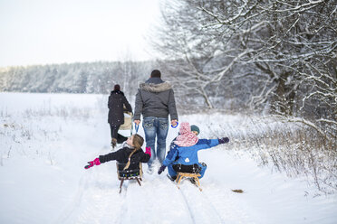 Germany, Brandenburg, back view of familiy with three children tobogganing - ASCF000473