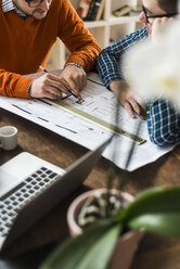 Zwei Kollegen besprechen einen Plan im Büro - UUF006385