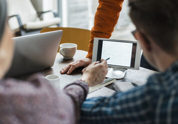 Kollegen im Büro diskutieren über eine digitale Tafel, die verschiedene Formen zeigt - UUF006395