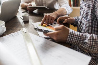 Colleagues at desk with smartphone, diagram and construction plan - UUF006400