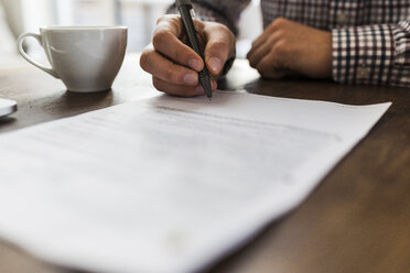 Close-up of man signing document on table - UUF006401