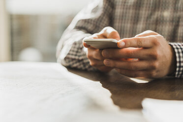 Close-up of man with cell phone at desk - UUF006411