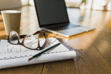 Laptop, notepad and glasses on wooden floor - UUF006418