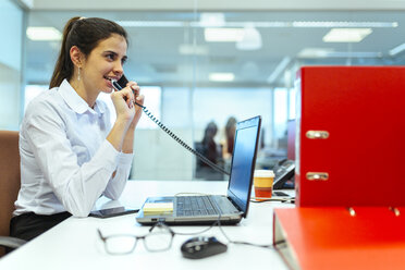 Junge Geschäftsfrau, die in einem Büro telefoniert - MGOF001314