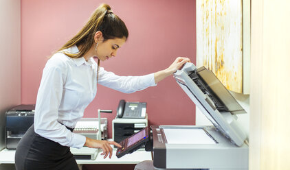 Junge Geschäftsfrau bei der Arbeit am Kopiergerät im Büro - MGOF001315