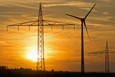 Germany, Bavaria, power pylons, wind wheel and evening sun - UMF000796