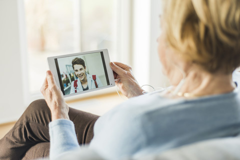 Senior woman looking at picture of young man on digital tablet stock photo