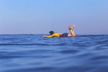 Indonesien, Bali, Frau auf ihrem Surfbrett liegend im Wasser treibend - KNTF000232