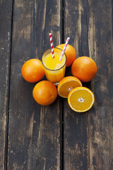 Ganze und geschnittene Orangen und ein Glas Orangensaft auf Holz - CSF027025