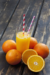 Whole and sliced oranges and glass of orange juice on wood - CSF027026