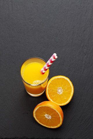 Aufgeschnittene Orange und Glas Orangensaft auf Schiefer, lizenzfreies Stockfoto