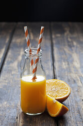 Sliced orange and bottle of orange juice on wood - CSF027030