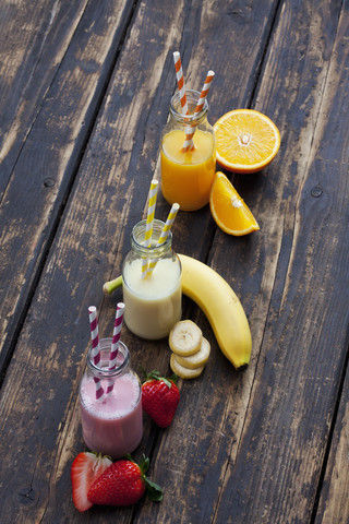 Reihe von drei Flaschen mit verschiedenen Fruchtsmoothies und Orangensaft, lizenzfreies Stockfoto