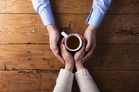 Hands of a young couple holding mug of tea stock photo