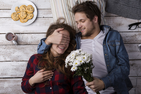 Junger Mann überrascht seine Freundin mit Blumen, lizenzfreies Stockfoto