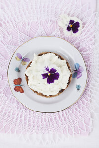 Scheibe Brot mit Frischkäse und Stiefmütterchen, essbare Blüte, auf Teller - GWF004602