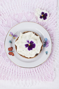 Slice of bread with cream cheese and pansy, eatable blossom, on plate - GWF004602