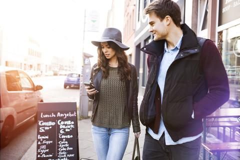 Germany, Berlin, young couple walking along sidewalk stock photo