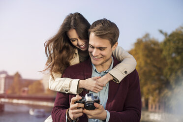 Deutschland, Berlin, glückliches junges Paar mit Blick in die Kamera am Ufer der Spree - GCF000141