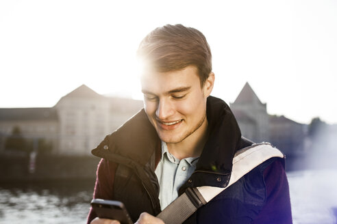 Germany, Berlin, young man holding smartphone at River Spree - GCF000163