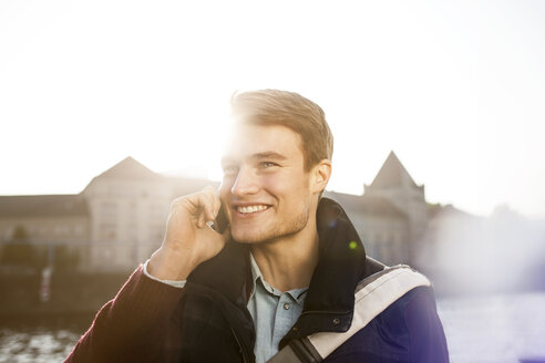 Deutschland, Berlin, junger Mann am Telefon an der Spree - GCF000164