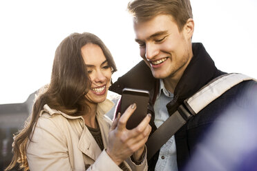 Smiling young couple looking at smartphone outdoors - GCF000170