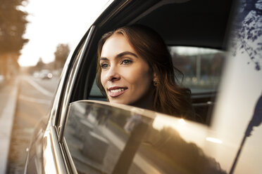 Lächelnde junge Frau schaut aus dem Autofenster - GCF000182