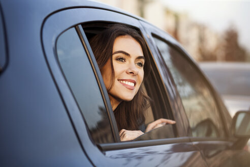 Lächelnde junge Frau schaut aus dem Autofenster - GCF000184