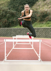 Sportliche Frau springt auf einer Laufbahn - MGOF001319