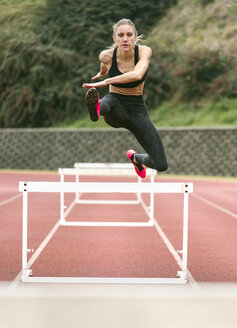 Athlete woman jumping in a running track - MGOF001319