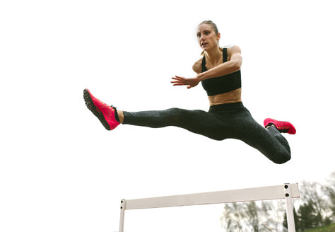 Athlete woman jumping in a running track - MGOF001320