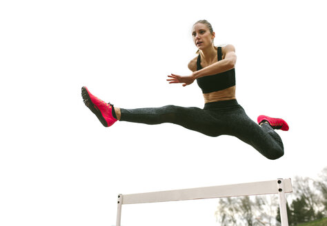 Sportliche Frau springt auf einer Laufbahn - MGOF001320