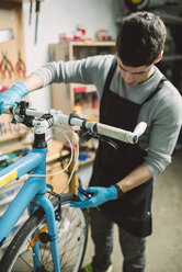 Mechanic repairing a bicycle in his workshop - RAEF000823